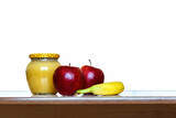 Still life on a white background. Jar of honey, red apples and banana on the table on a white background