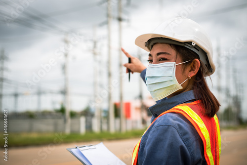 Female engineer pointing to a high voltage pole.