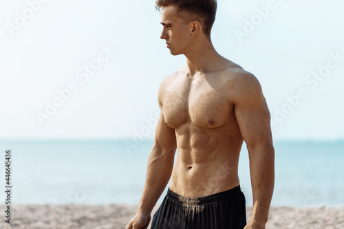 Portrait of strong healthy sporty man, training athlete outdoors, handsome sporty man outdoors on the beach
