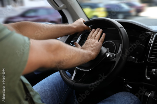 Man pressing horn in car, closeup. Aggressive driving behavior