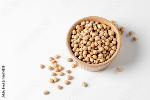 dry chickpeas, in a ceramic dish on a white table, top view, empty space for text