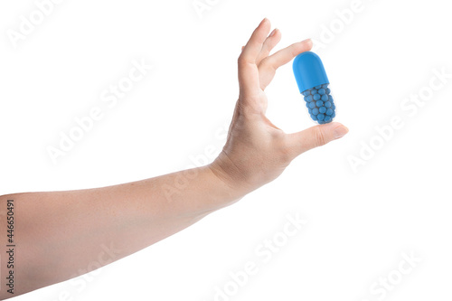Female hand holding giant blue pill isolated on white background