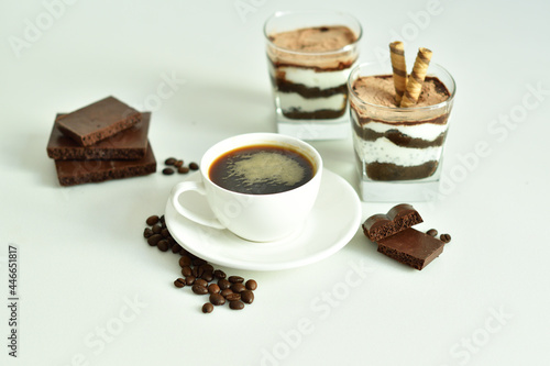 cup of black coffee and coffee beans, dessert in a glass. Cheesecake with chocolate and cottage cheese cream