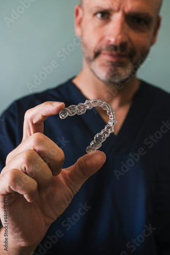 Male doctor holds a transparent dental aligner with his hand