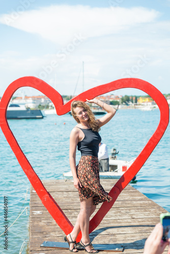 woman near heart shape photo spot at sea beach