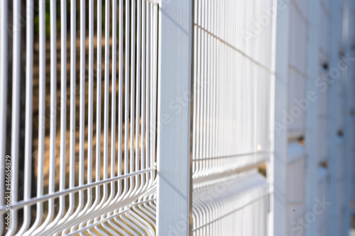 Elements of a metal vertical fence with a strong background blur, the park territory is free of COVID-19