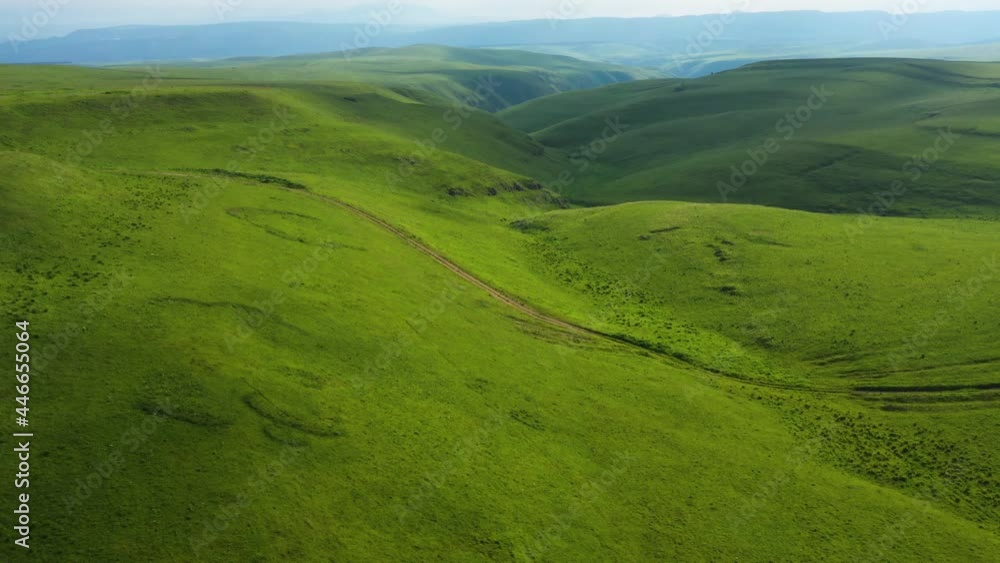 Drone Flight above long dirt road in the green fields . Aerial view on the beautiful summer landscape with country road and green fields Drone Flight above long dirt road in the green fields . Aerial view on the beautiful summer landscape with country road and green fields