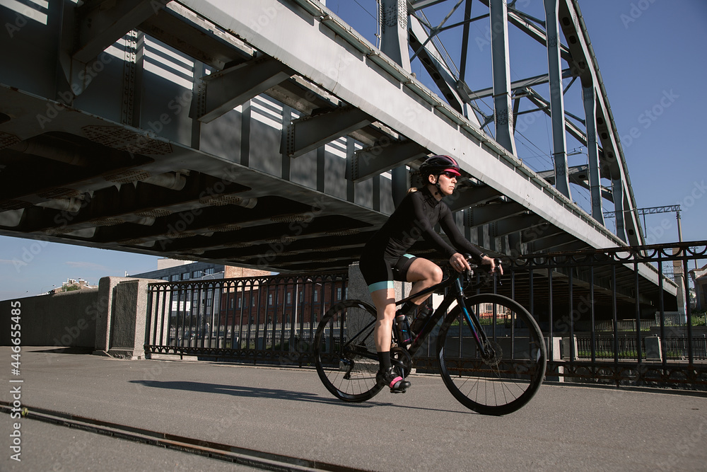 Obraz premium A cyclist trains in the morning in the city on the waterfront. Cycling in the city. Preparing for the competition.
