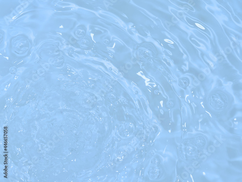 De-focused blurred transparent blue colored clear calm water surface texture with splashes and bubbles. Trendy abstract nature background. Water waves in sunlight with copy space.