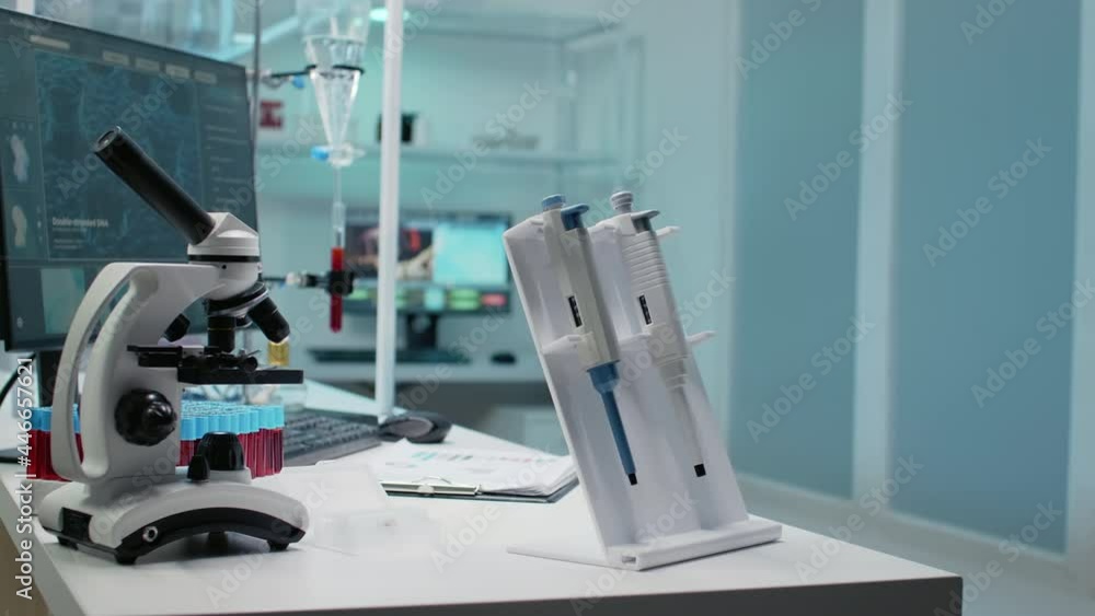 Close up of micro pipette tool and medical equipment in empty laboratory. Nobody in microbiology room with microscope, vacutainers and blood sample as research instruments on desk Close up of micro pipette tool and medical equipment in empty laboratory. Nobody in microbiology room with microscope, vacutainers and blood sample as research instruments on desk