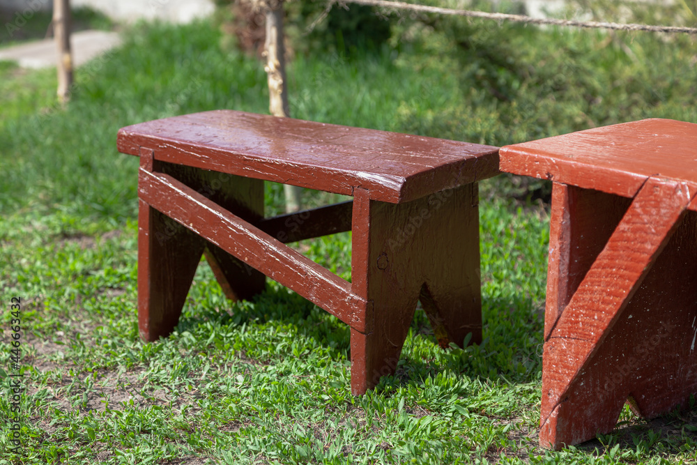 Two wooden benches stand on green grass Two wooden benches stand on green grass