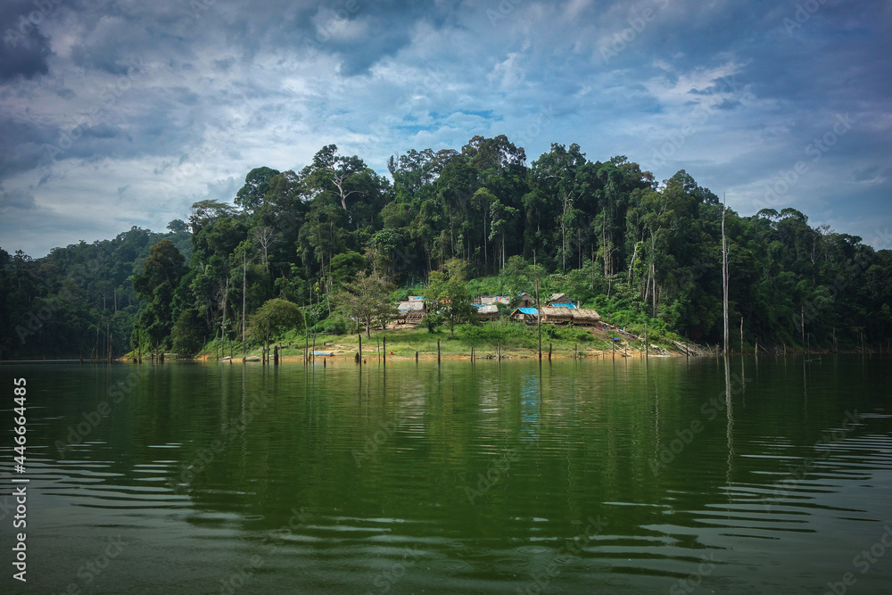 a rain forest scenic of orang asli village in the lake with cloudy sky background.