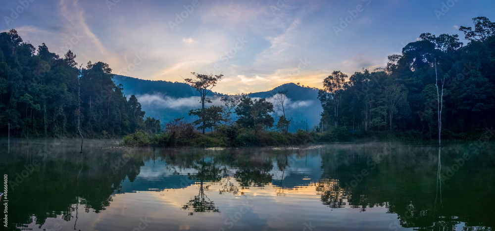 Dramatic reflecting scenic view of a lake in the forest during foggy morning Dramatic reflecting scenic view of a lake in the forest during foggy morning