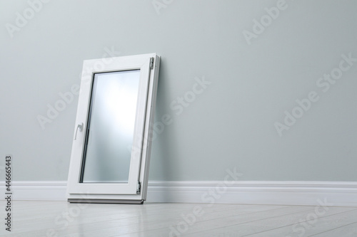 Modern single casement window near light grey wall indoors, space for text photo