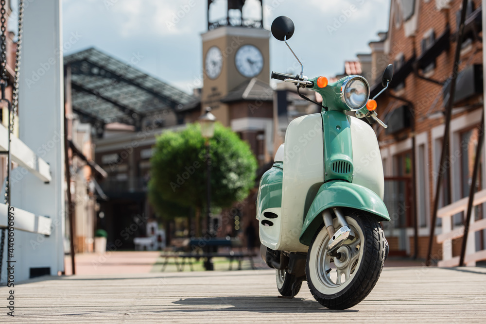 scooter on urban street near buildings and clock tower on blurred background