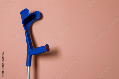 Elbow crutch on pale pink background. Space for text photo