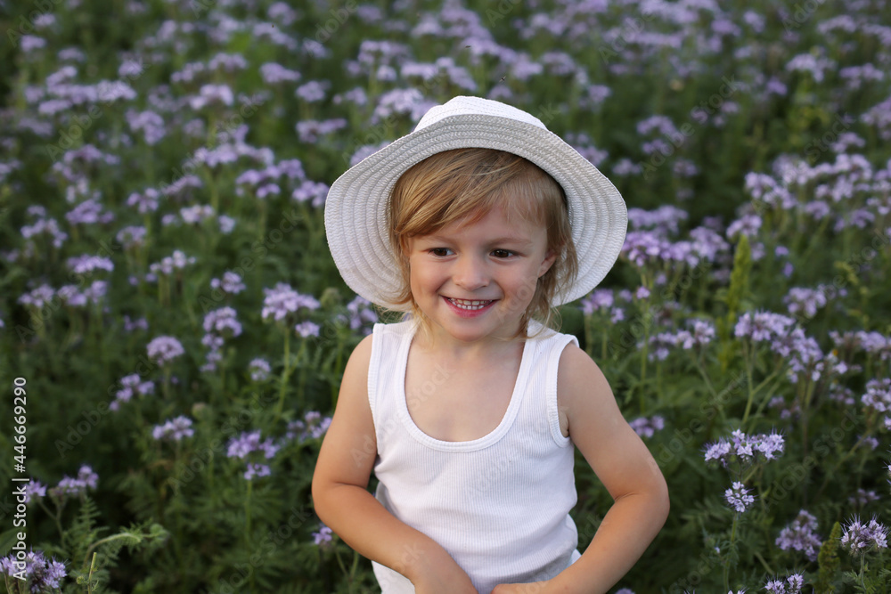 a beautiful blond boy is standing in a field with purple flowers smiling a beautiful blond boy is standing in a field with purple flowers smiling