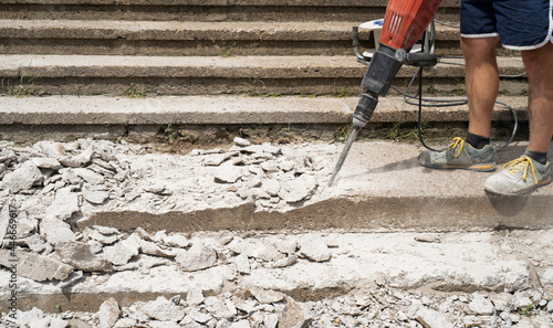 Photos construction worker with a jackhammer, renovation of stairs, crushing the surfac