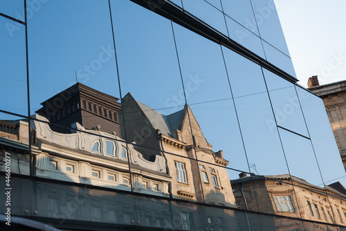 the facade of the old building is reflected in the glass facade of the new building