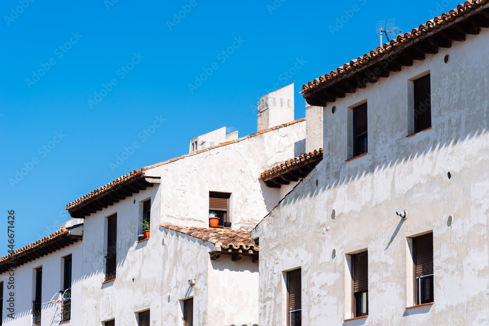 Traditional houses in the town of Chinchon. Old weathered white facades of residential building agaisnt blue sky