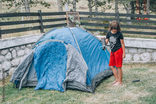 Boy in nature, in the forest sets up a tent and equips a bivouac. Summer hiking trip. Holidays in nature outdoor
