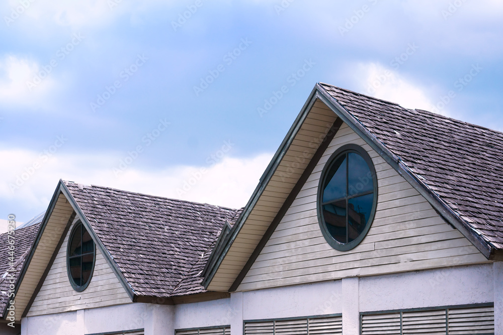Beautiful wooden house roof with a round window on blue sky background