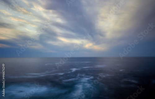 calm horizon with clouds that move quickly in the sky and a sea with areas of water foam and currents
