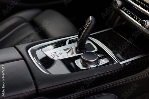 Automatic gear shift knob in a modern sports limousine car. Black car interior.