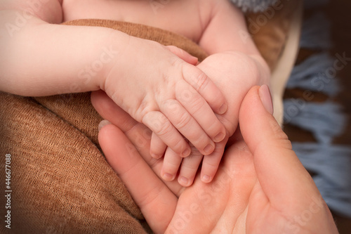Newborn baby holding mother's finger, Close up photo of hands of newborn baby and woman.