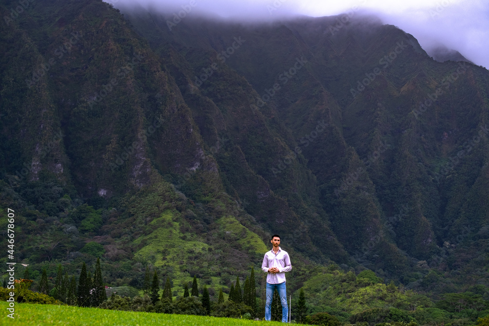 Man standing in front of mountains in Hawaii Man standing in front of mountains in Hawaii