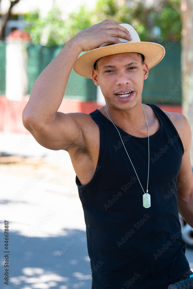 Handsome latino man holding his hat in place: Selective focus. Diversity and lifestyle concept.