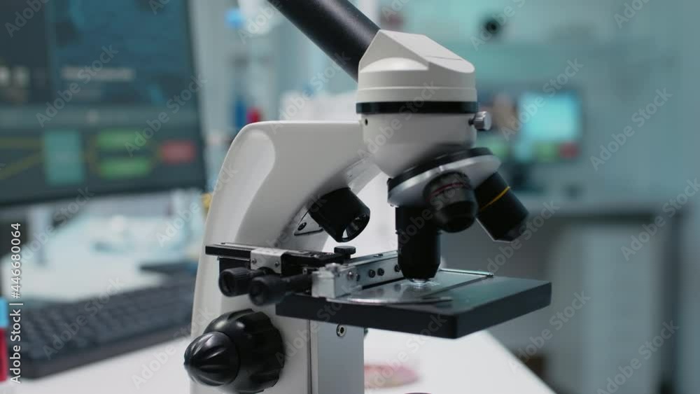 Close up of scientific microscope in laboratory using optical lens with magnifying glass for dna test on tray. Empty room with chemical equipment for sample and substance examination Close up of scientific microscope in laboratory using optical lens with magnifying glass for dna test on tray. Empty room with chemical equipment for sample and substance examination