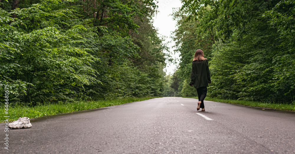 A young girl walks along the road in the forest