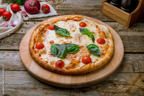 Italian pizza Margherita with basyl on wooden table