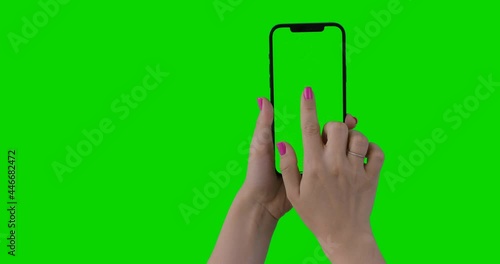 Woman hand holding the smartphone on green screen chroma key background. Bonus 20 Gestures Set. Phone mock-up for your product. iPhone 12 Pro Max in vertical orientation portrait mode. Alpha Channel.