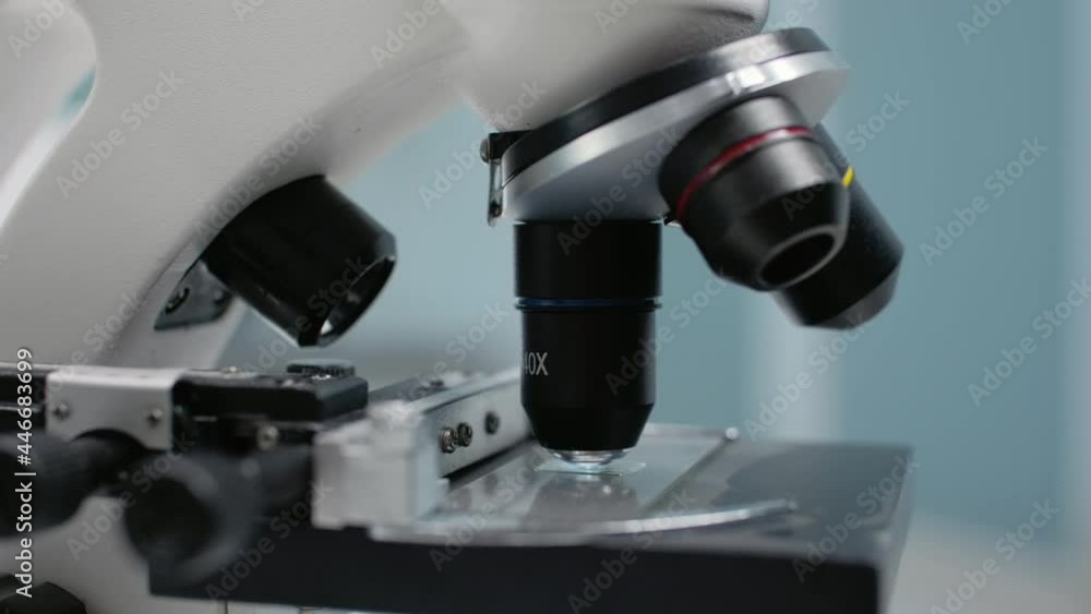 Close up of microscopic sample glass tray in laboratory. Microscope for optical test analysis with magnifying lens used in dna and bacteria research investigation and lab industry Close up of microscopic sample glass tray in laboratory. Microscope for optical test analysis with magnifying lens used in dna and bacteria research investigation and lab industry