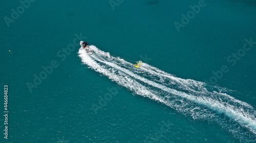 Aerial photo of extreme power boat donut water-sports cruising in high speed in tropical emerald bay