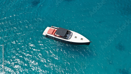 Aerial drone photo of small luxury speed boat cruising in deep blue waters of Mykonos island, Cyclades, Greece