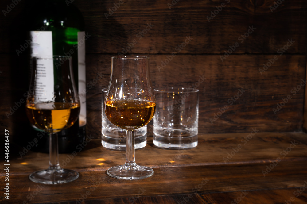 Glasses of strong scotch single malt whisky served on dark wooden table in old pub Glasses of strong scotch single malt whisky served on dark wooden table in old pub