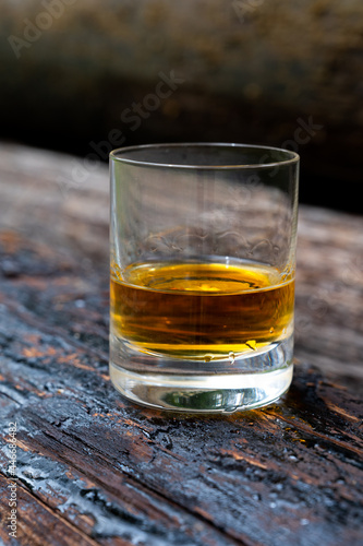 Glass of strong scotch single malt whisky on old log soaked in creosote