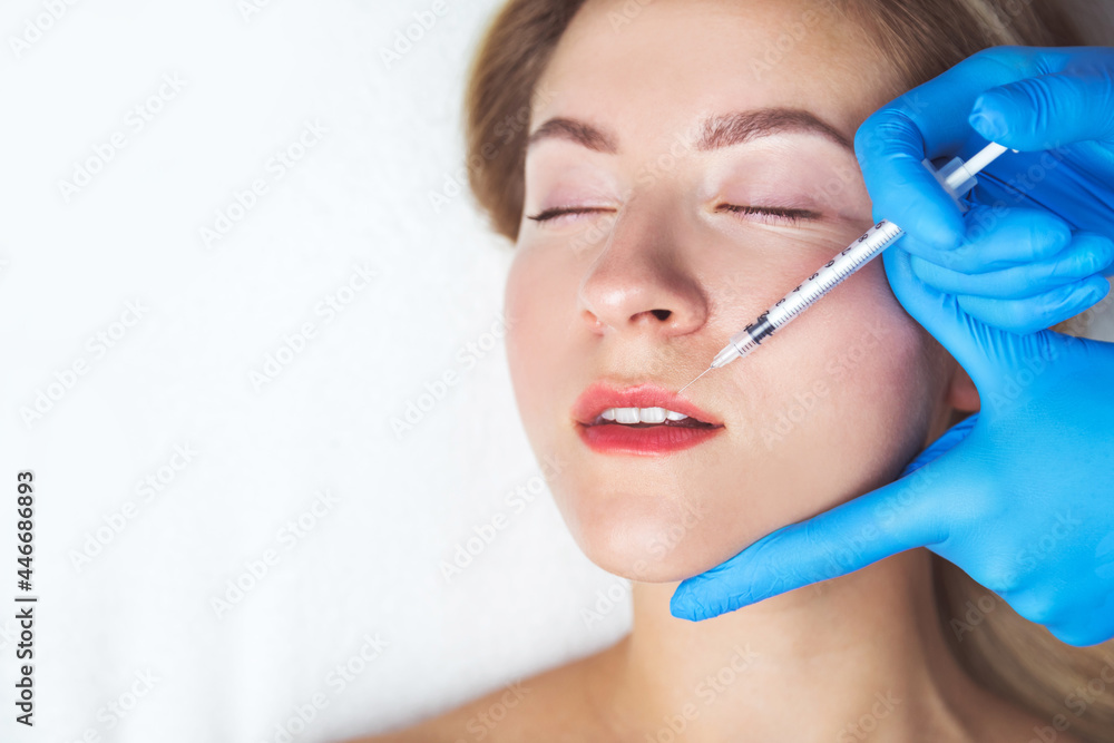 The doctor cosmetologist makes Lip augmentation procedure of a beautiful woman in a beauty salon.Cosmetology skin care. The doctor cosmetologist makes Lip augmentation procedure of a beautiful woman in a beauty salon.Cosmetology skin care.