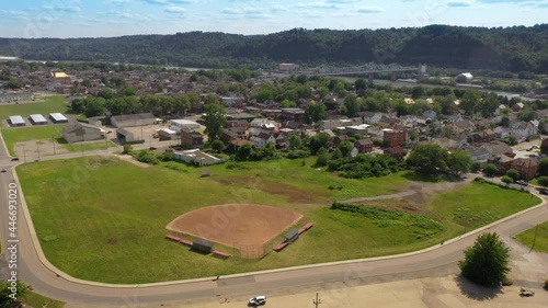 A slowly orbiting aerial view of a small Pennsylvania river town. A baseball sandlot field in the foreground and the Ambridge Bridge over the Ohio River in the distance.  	 photo