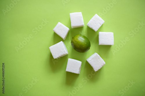 Natural and homemade marshmallows and limes on green background