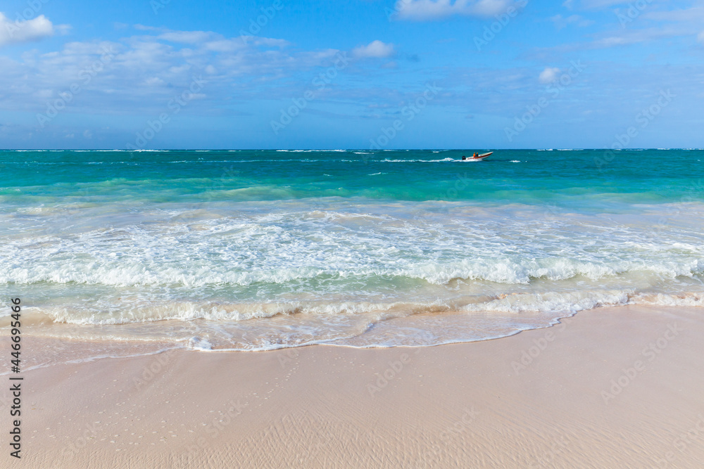 Small motorboat goes along the Bavaro beach on a sunny day