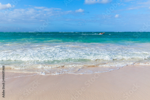 Small motorboat goes along the Bavaro beach on a sunny day