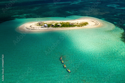 Aerial view of tropical island Ilet Caret, with sandy beach and blue sea with four jet skis in line, in the Grand Cul de Sac Marin, Sainte Rose, Les Antilles, Guadeloupe, Eastern Caribbean Island.