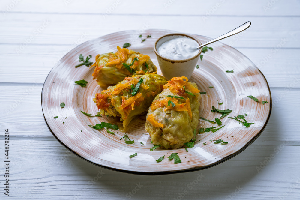 Stuffed cabbage with sour cream on white wooden table Stuffed cabbage with sour cream on white wooden table