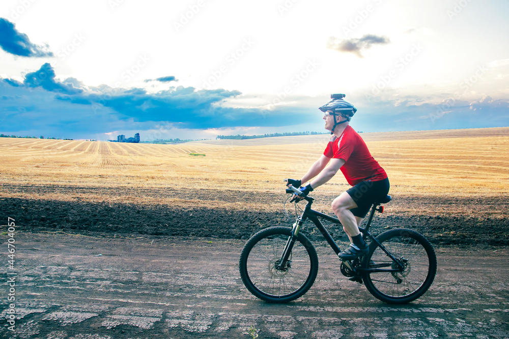 Obraz premium cyclist rides a bike on the road near the field. Outdoor sports. Healthy lifestyle.