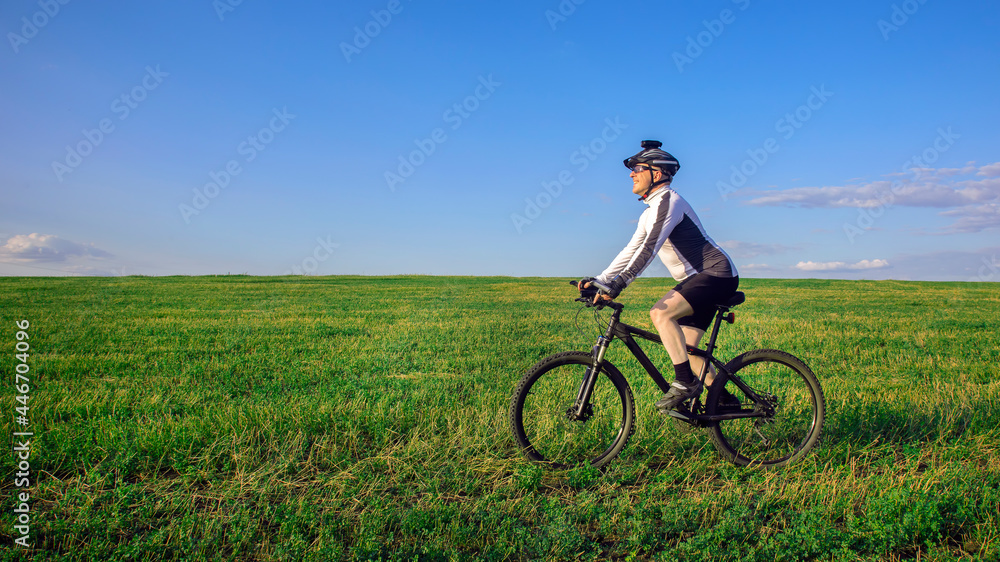 The cyclist rides a bicycle on the green grass on the field. Outdoor sports. Healthy lifestyle. The cyclist rides a bicycle on the green grass on the field. Outdoor sports. Healthy lifestyle.