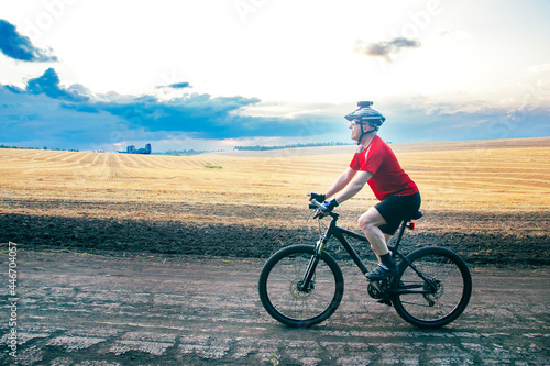 cyclist rides a bike on the road near the field. Outdoor sports. Healthy lifestyle.